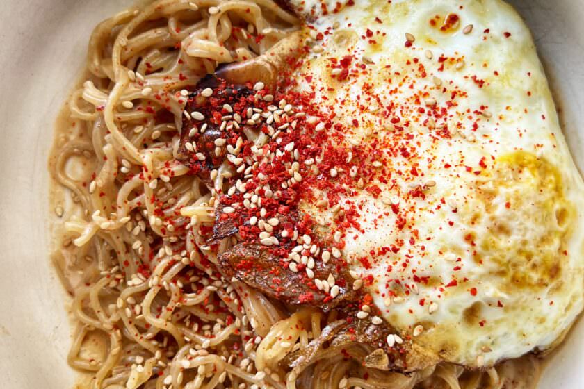 creamy sesame noodles topped with a fried egg, chilli flakes, and sesame seeds